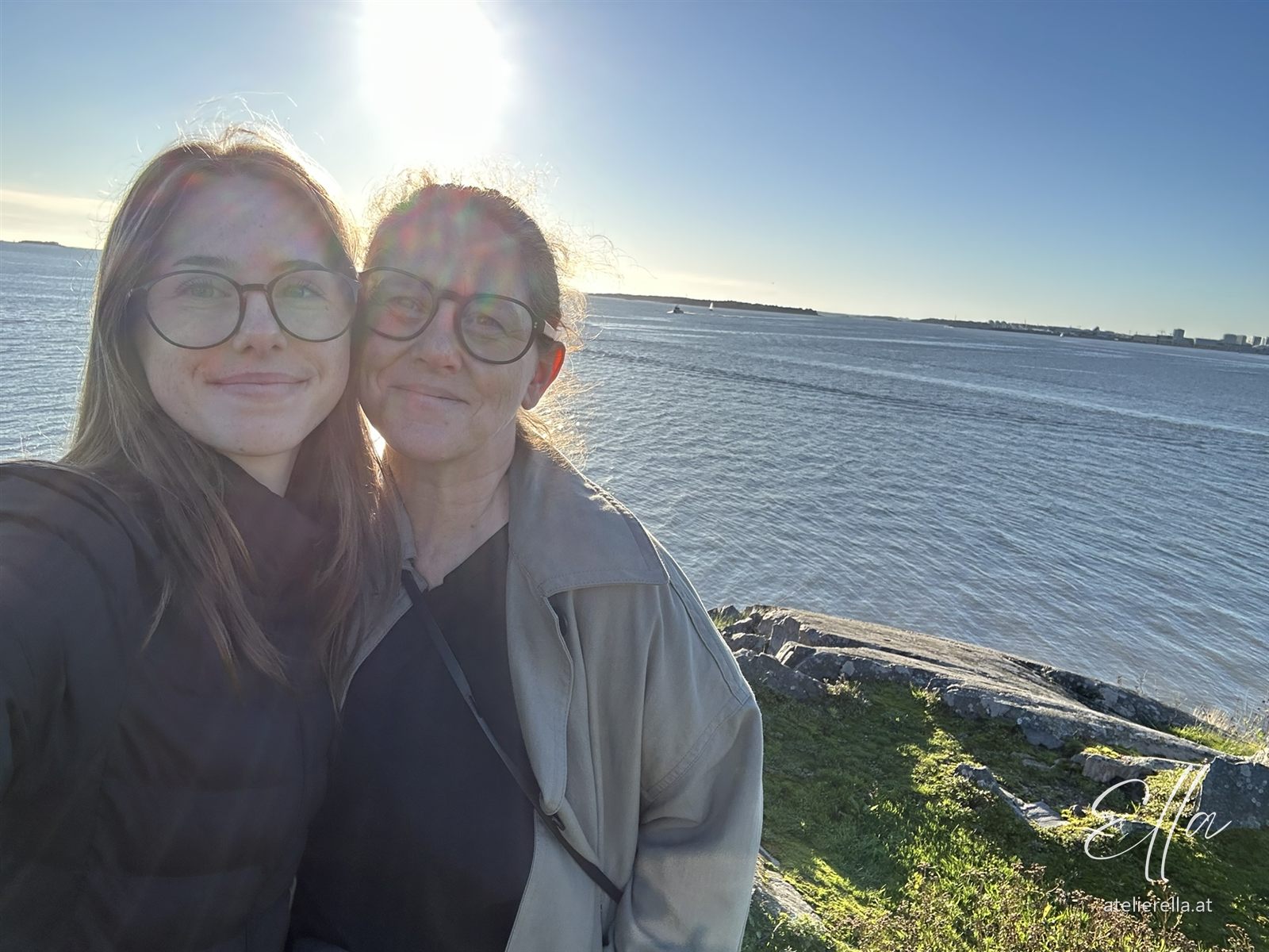 Ella und ihre Tochter lächeln in die Kamera, dahinter das Meer bei Suomenlinna