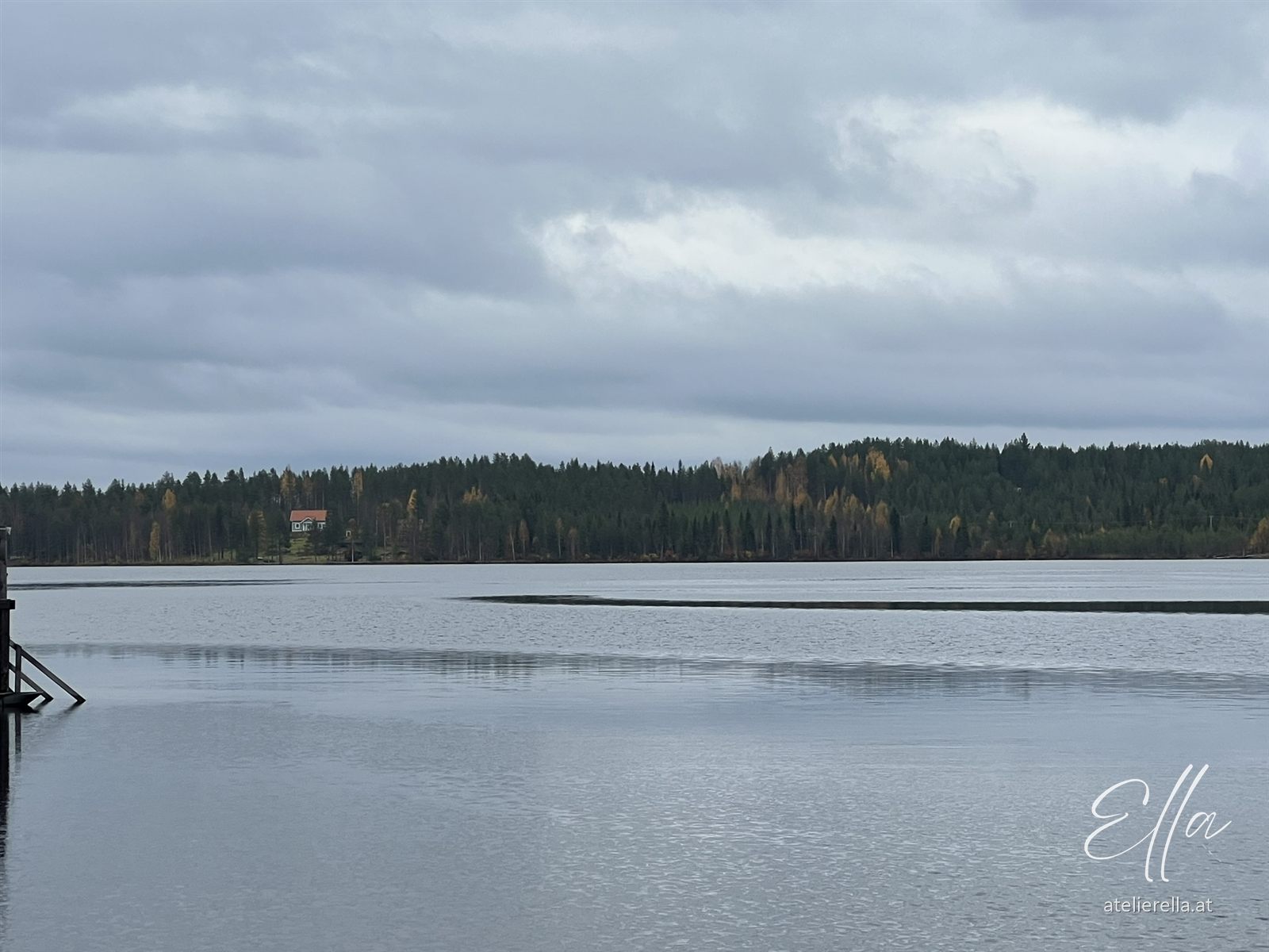 Weiter Blick über einen See mit Wald am Horizont