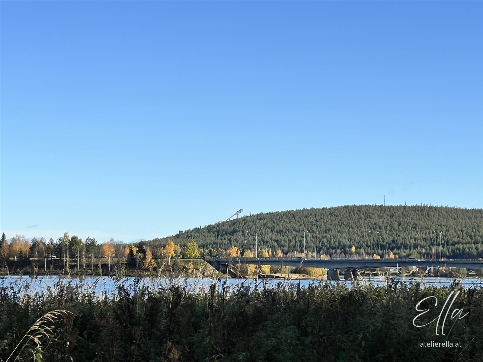 Bewaldeter Hügel hinter einem See in Lappland