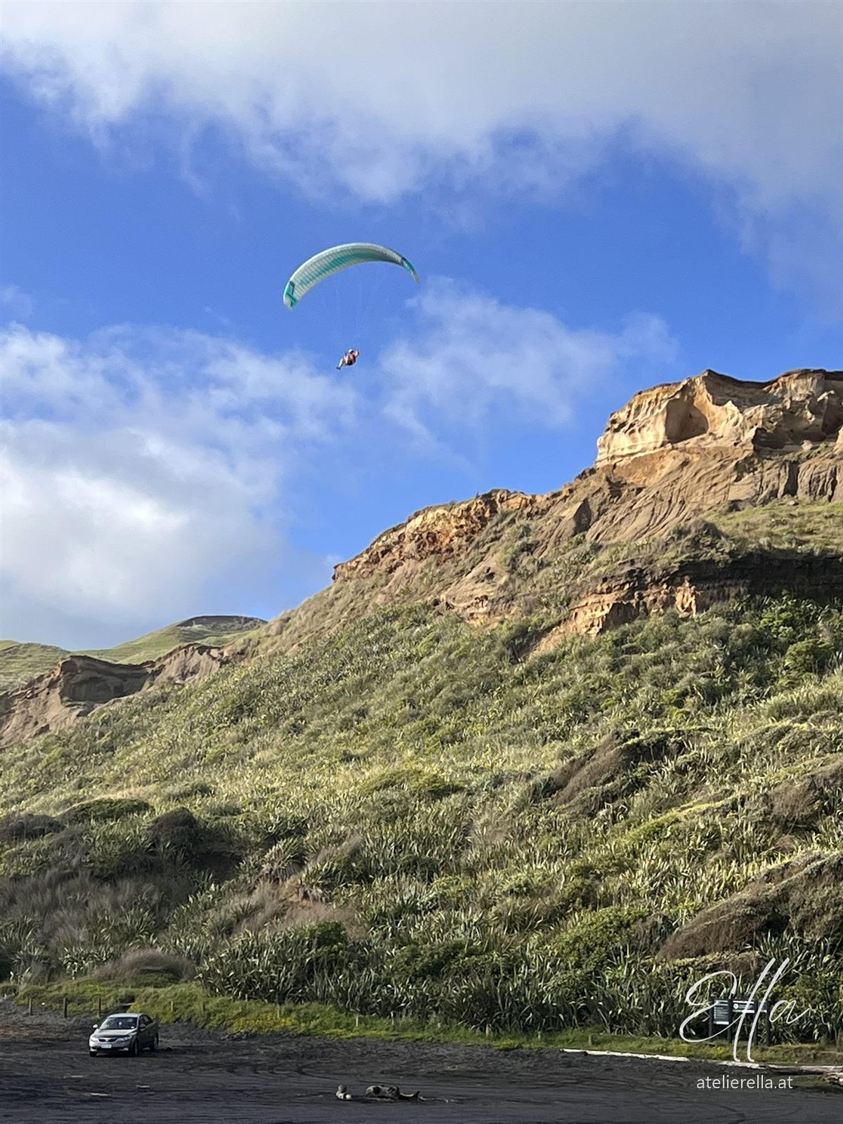 Paragleiter über grünen Klippen an der Westküste Neuseelands