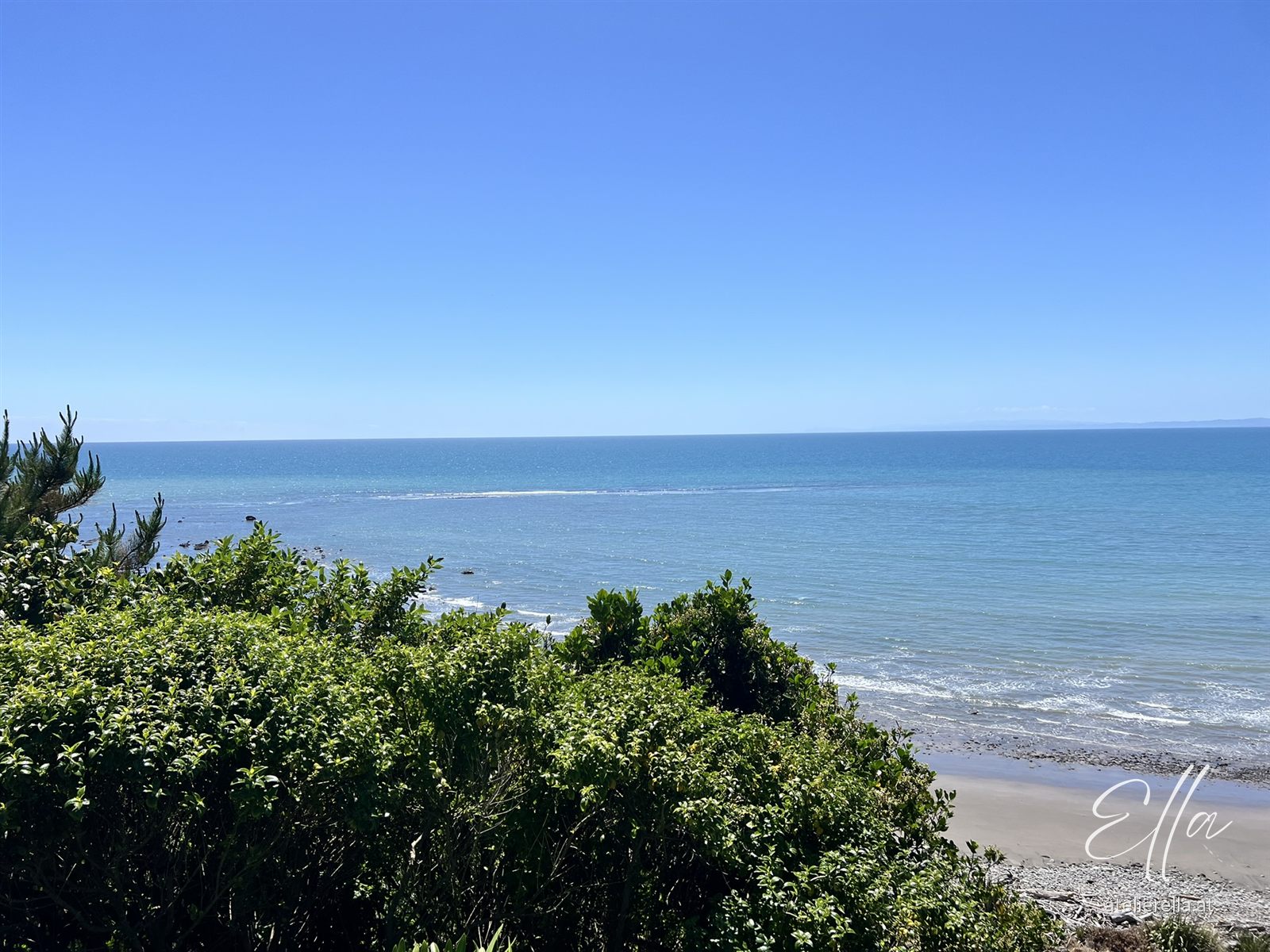 Blick über grüne Büsche auf das blaue Meer
