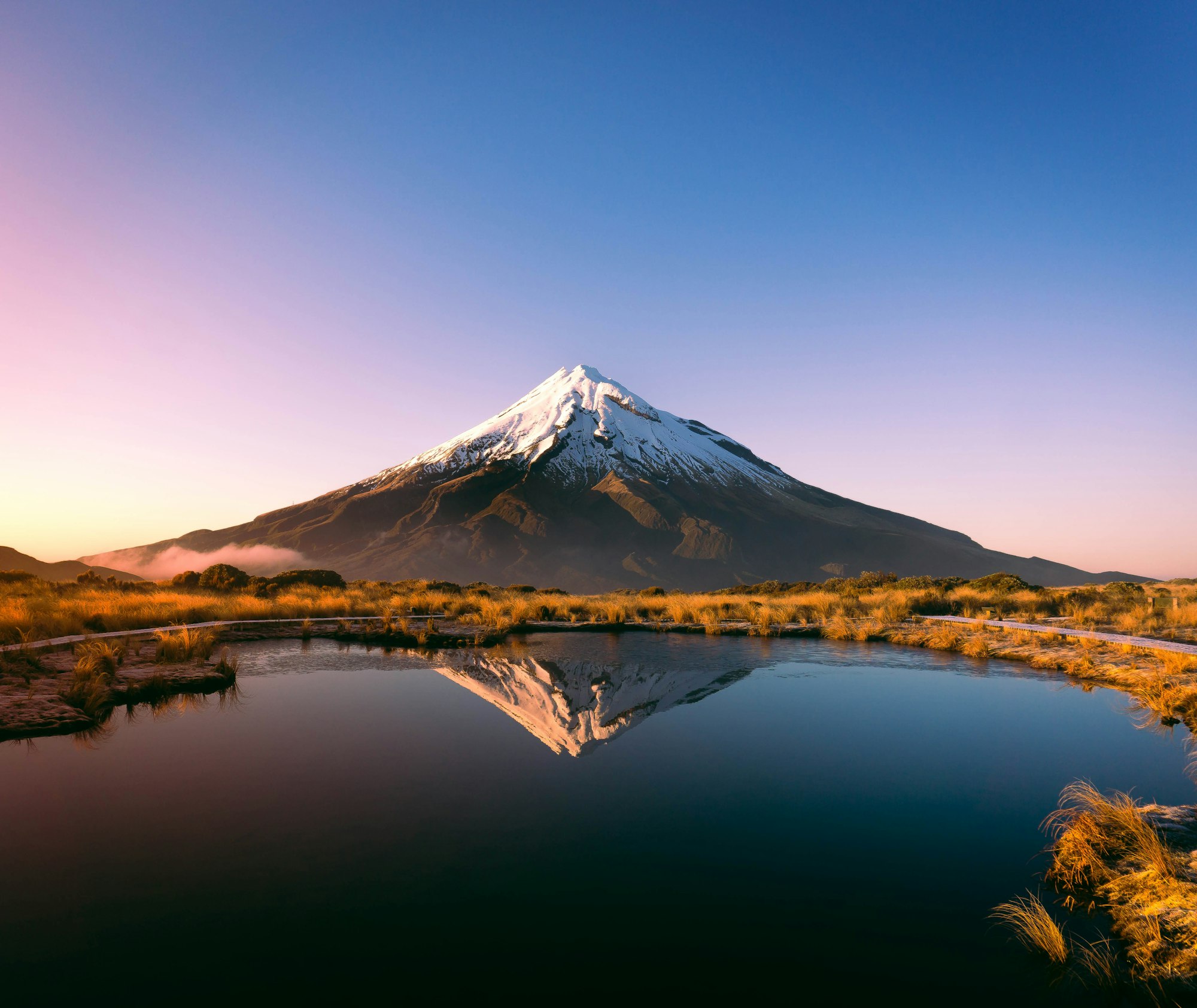 Schneebedeckter Vulkan Taranaki spiegelt sich im Morgenlicht in einem Bergsee