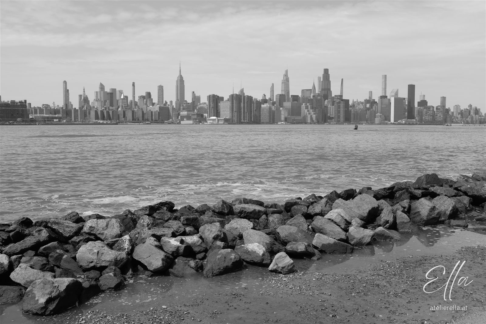 Skyline von Manhattan vom Wasser aus mit Steinen im Vordergrund, schwarz-weiß