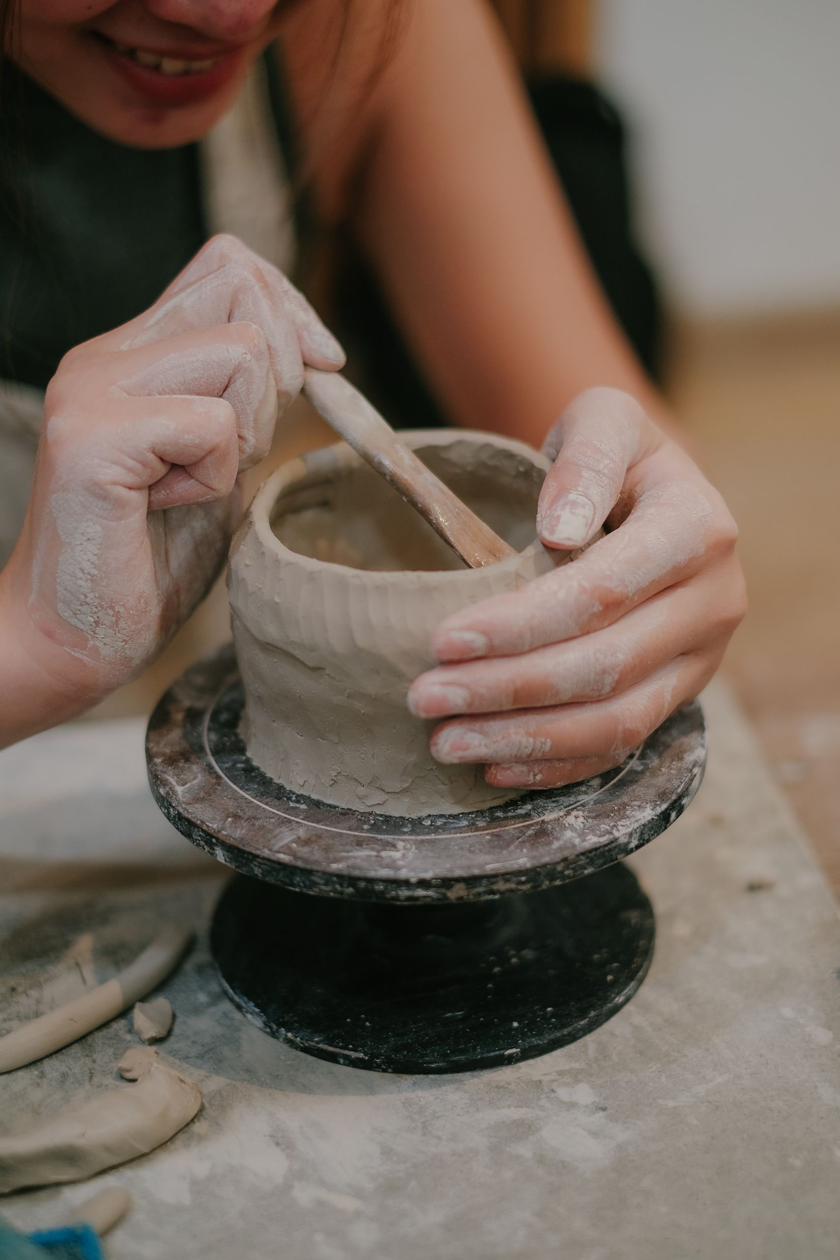 Close-up of a woman shaping a clay pot on a pottery wheel, showcasing craftsmanship.